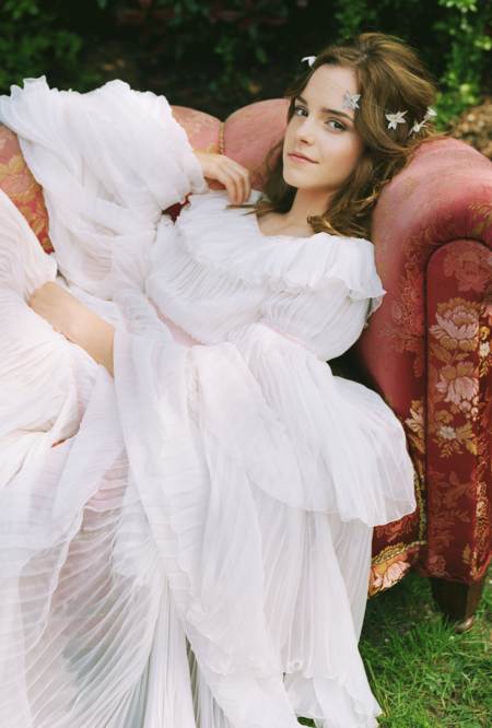 Emma Watson con un vestido largo blanco y acostada en un sillon