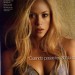 Shakira con el cabello totalmente rubio Shakira recargada en una pared, usando una blusa escotada