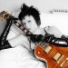 Mujer en fotografía blanco y negro, con una guitarra Les Paul que resalta en color café Fotografía de una mujer acostada, semidesnuda y con una guitarra a su lado