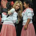 Shakira abrazando a dos niñas que visten trajes tipicos