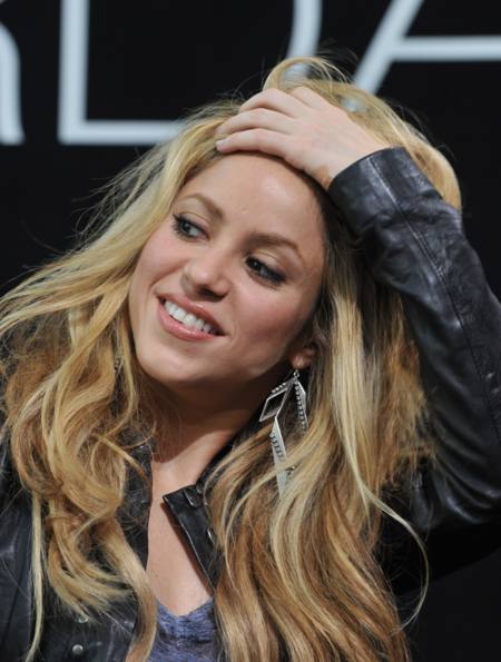 Shakira acomodandose el cabello mientras sonrie