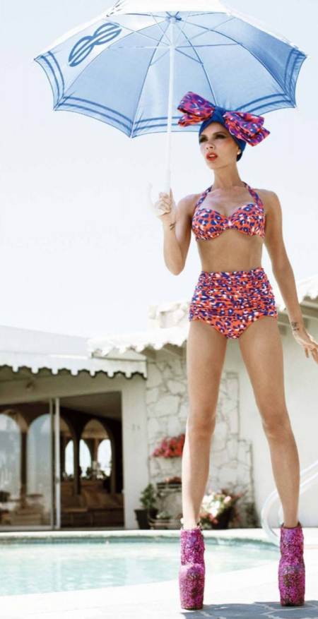 Victoria Beckham posando con traje de baño sosteniendo una sombrilla