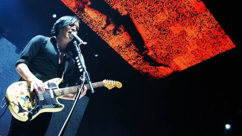 Brian Molko en el escenario con imagenes en la pantalla