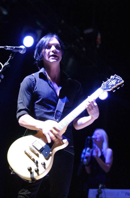 Brian Molko tocando la guitarra luciendo fashion