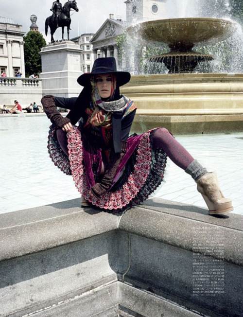 Dree Hemingway con falda tops sombrero y botas posando en una fuente