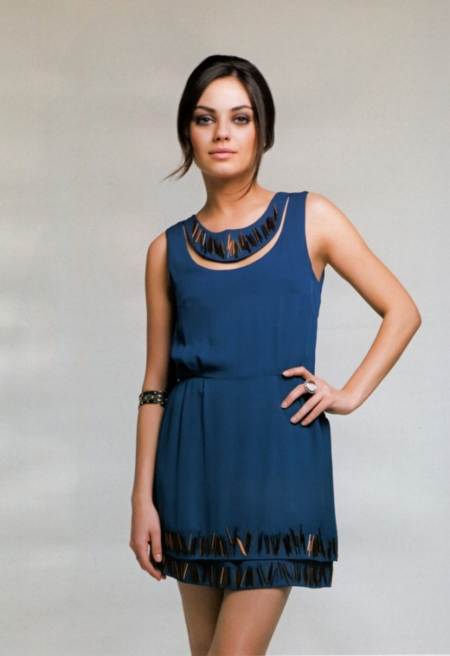Mila Kunis posando con vestido azul y un elegante peinado