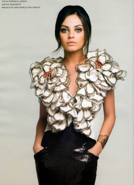 Mila Kunis posando con blusa floreada y con faldon negro