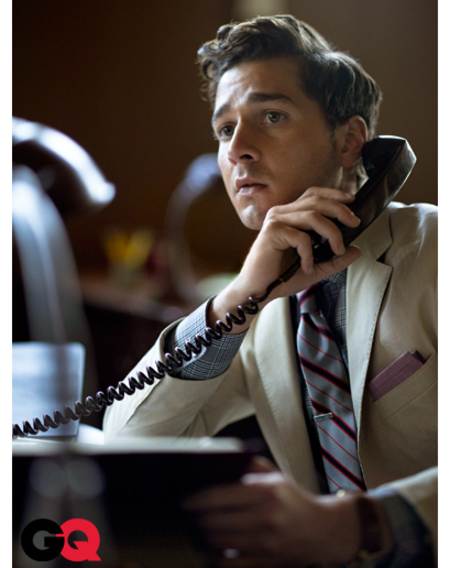 Shia LaBeouf con un traje ejecutivo claro mientras llama por telefono