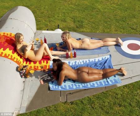 Chicas tomando el sol desnudas sobre un avion de guerra