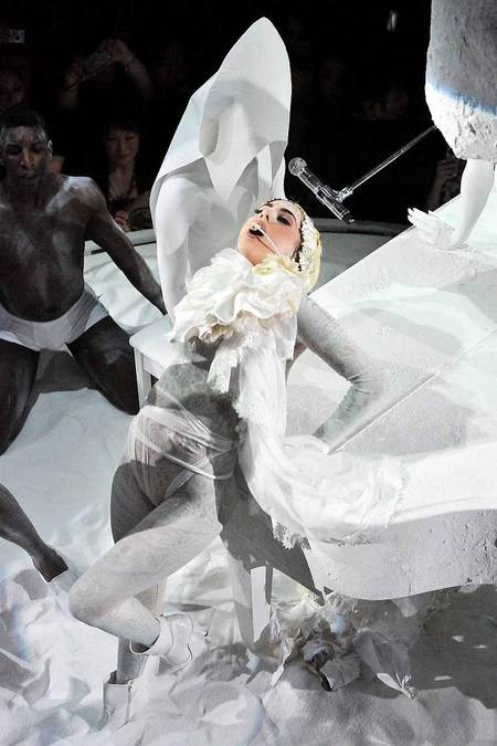Lady GaGa con una pose dramatica sobre el piano