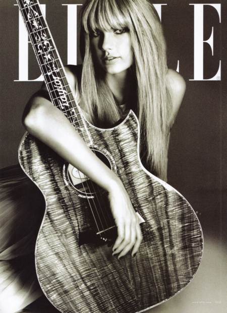 Taylor Swift con pelo lacio abrazando una guitarra electroacustica