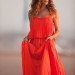 Carrie con un glamouroso vestido naranja caminando por la arena