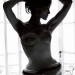 Foto de Angelina Jolie a blanco y negro, con corsé color blanco recargada sobre una ventana.