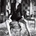 Angelina Jolie sonriendo sentada, con un traje de pantalón corto y saco color negro.