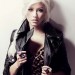 Christina Aguilera posando con una chaqueta color negro, maquillaje no muy cargado y su cabello rubio platino entrenzado.