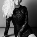 Christina Aguilera posa sentada, vistiendo un ajustado vestido corto de cuero con mangas largas.
