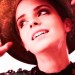 Emma Watson, mirando hacia otro lado, mientras sostiene un sombrero sobre su cabeza con sus manos