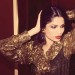 Freida Pinto posando sexy con una blusa con olanes color dorado y chaleco en un tono café